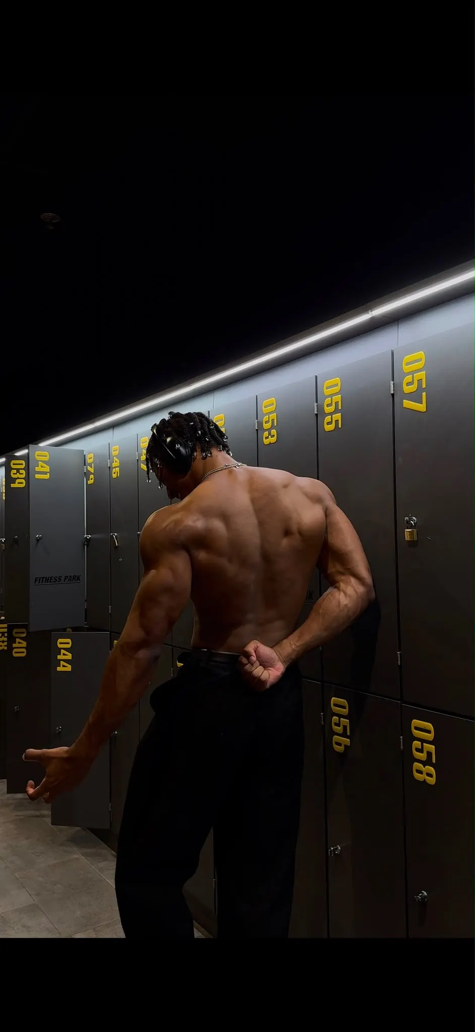 Tyron de dos devant des casiers de vestiaire, muscles du dos contractés